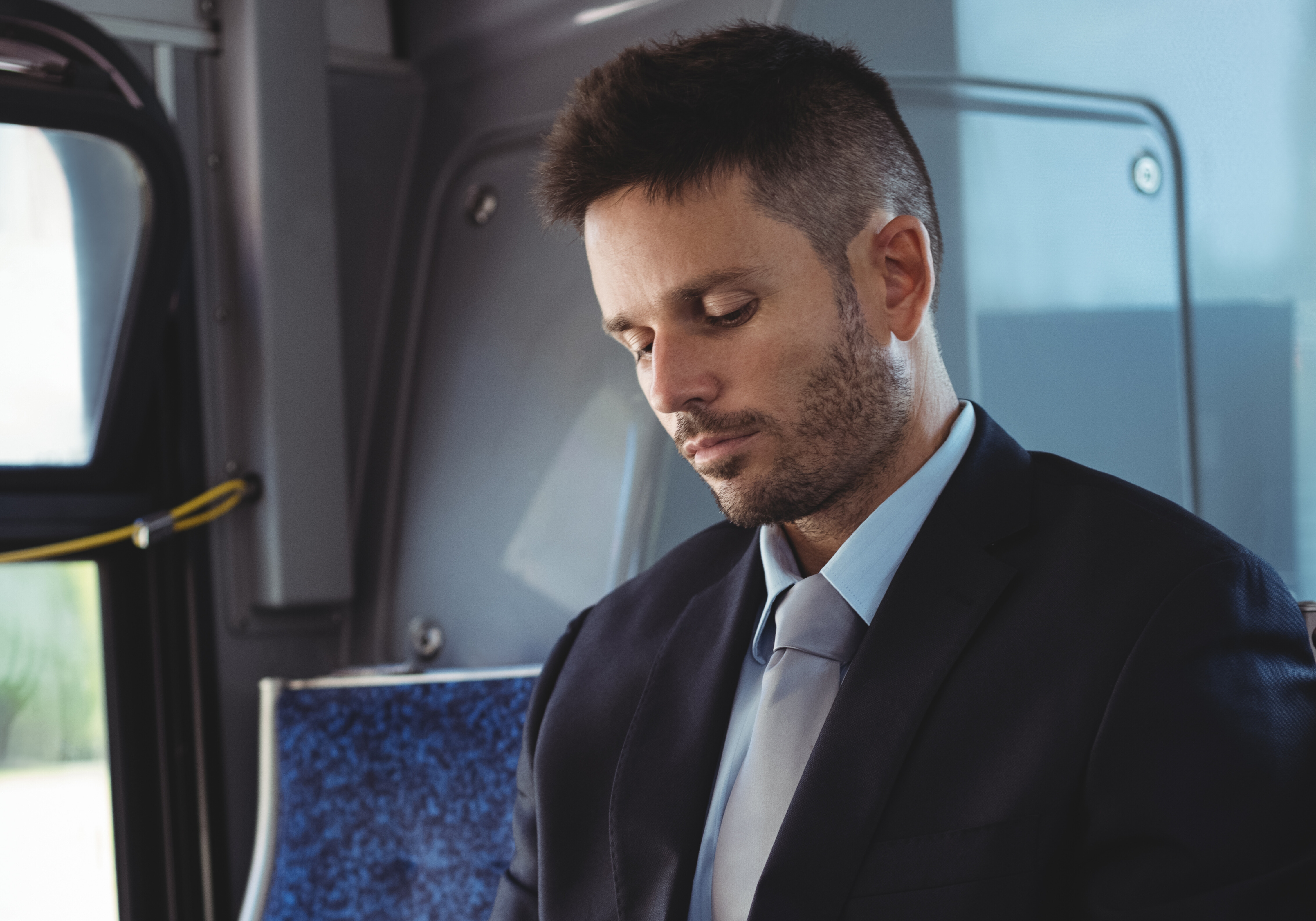 Professional dressed man standing next to corporate charter bus with city background