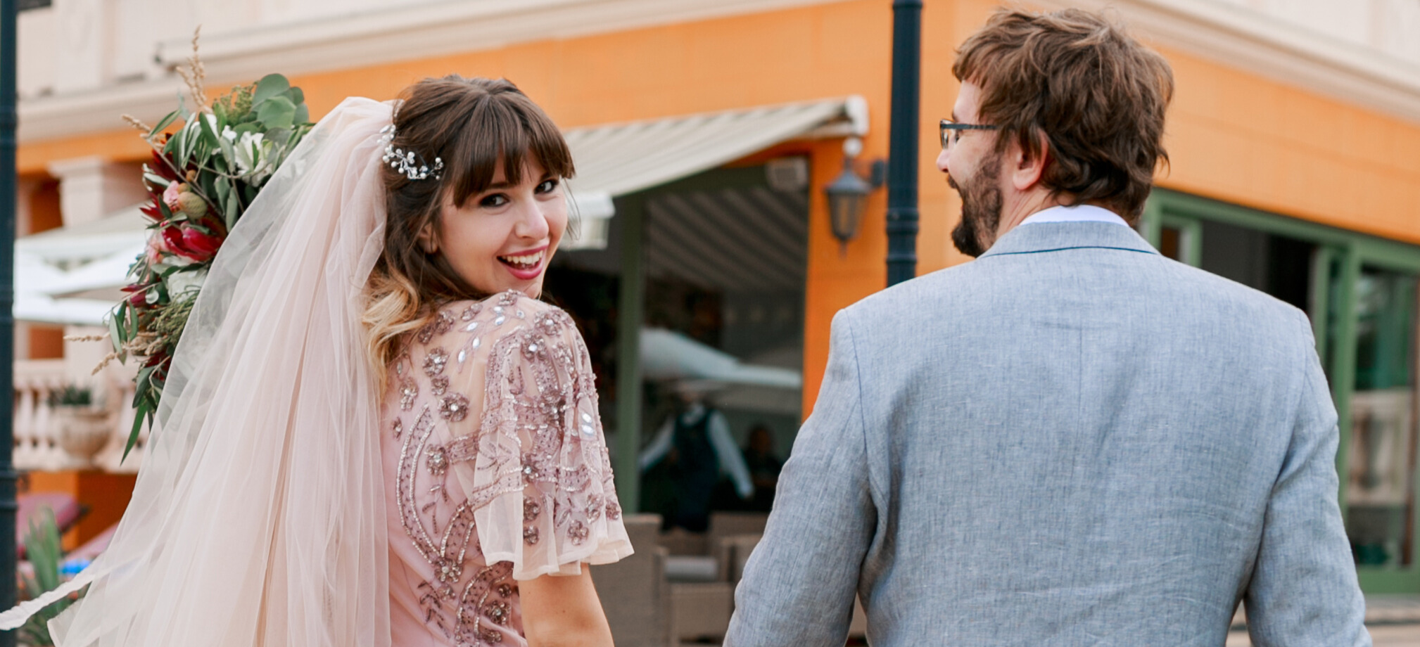 Bride and groom smiling outside decorated wedding charter bus on their special day