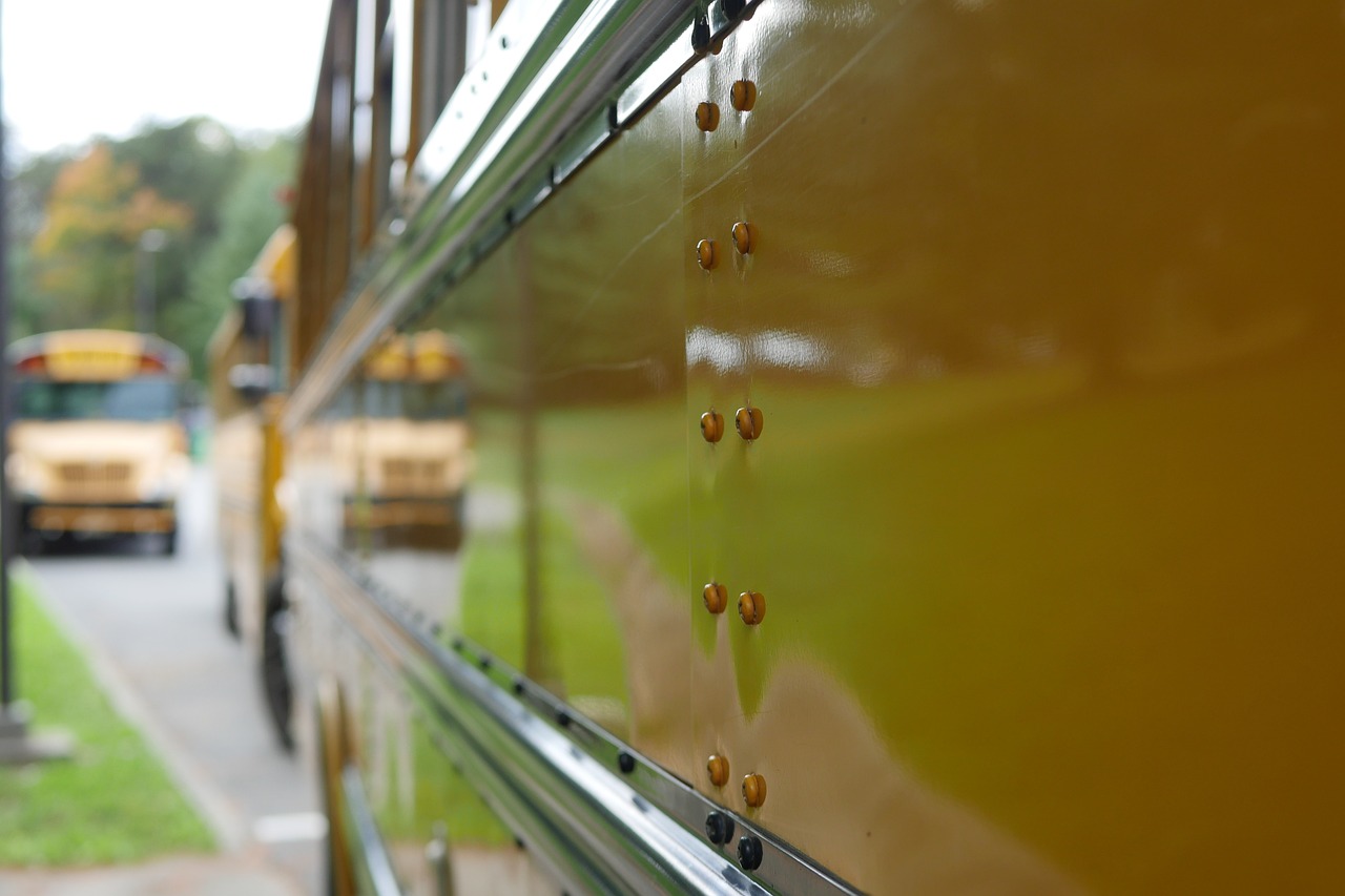 Happy children boarding a yellow school bus with a smiling driver